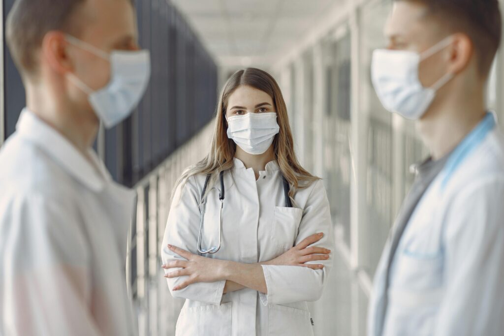 Medical professionals wearing face masks in a hospital hallway.