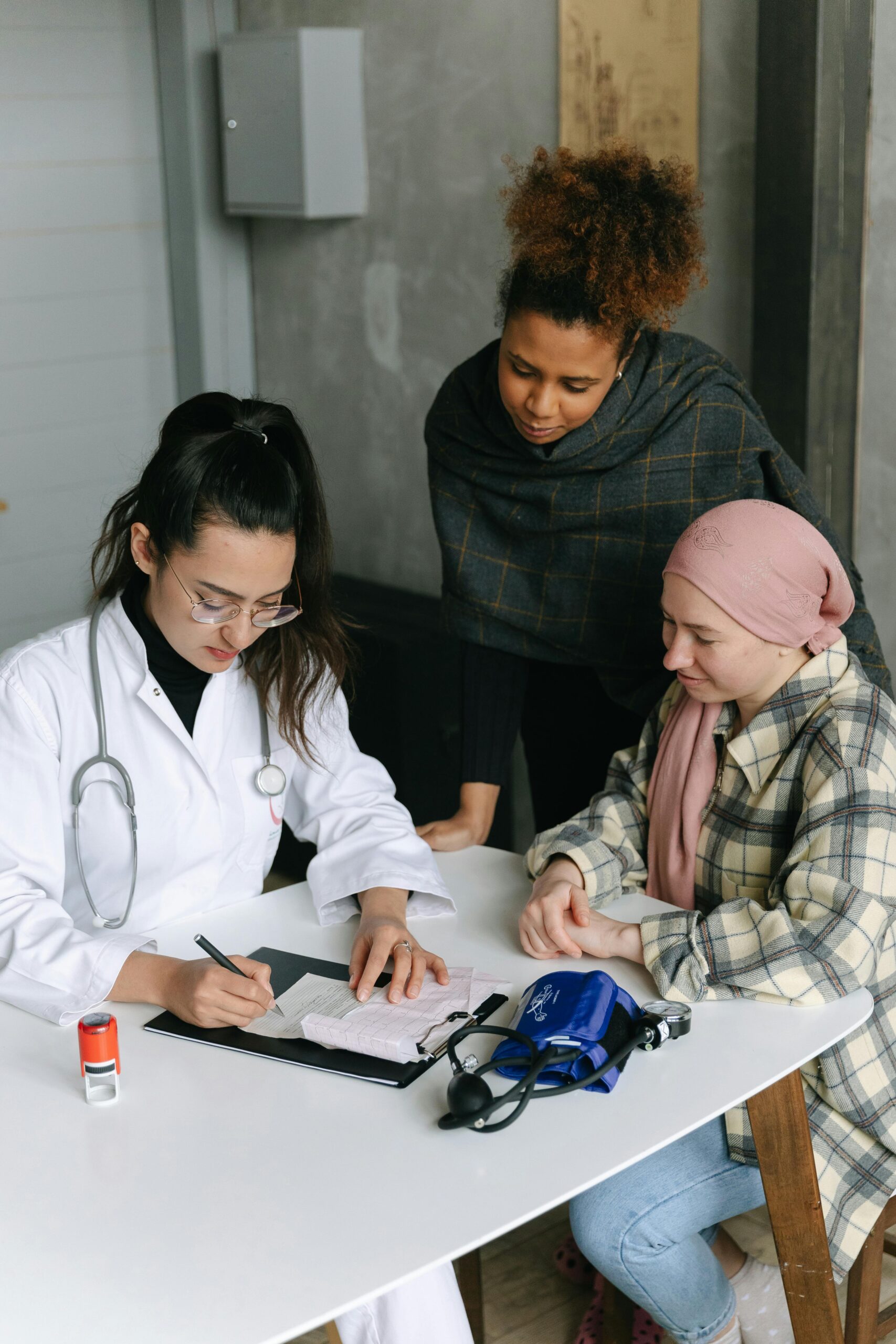 A female doctor consults two patients at a desk in a medical clinic, emphasizing diversity and professionalism.