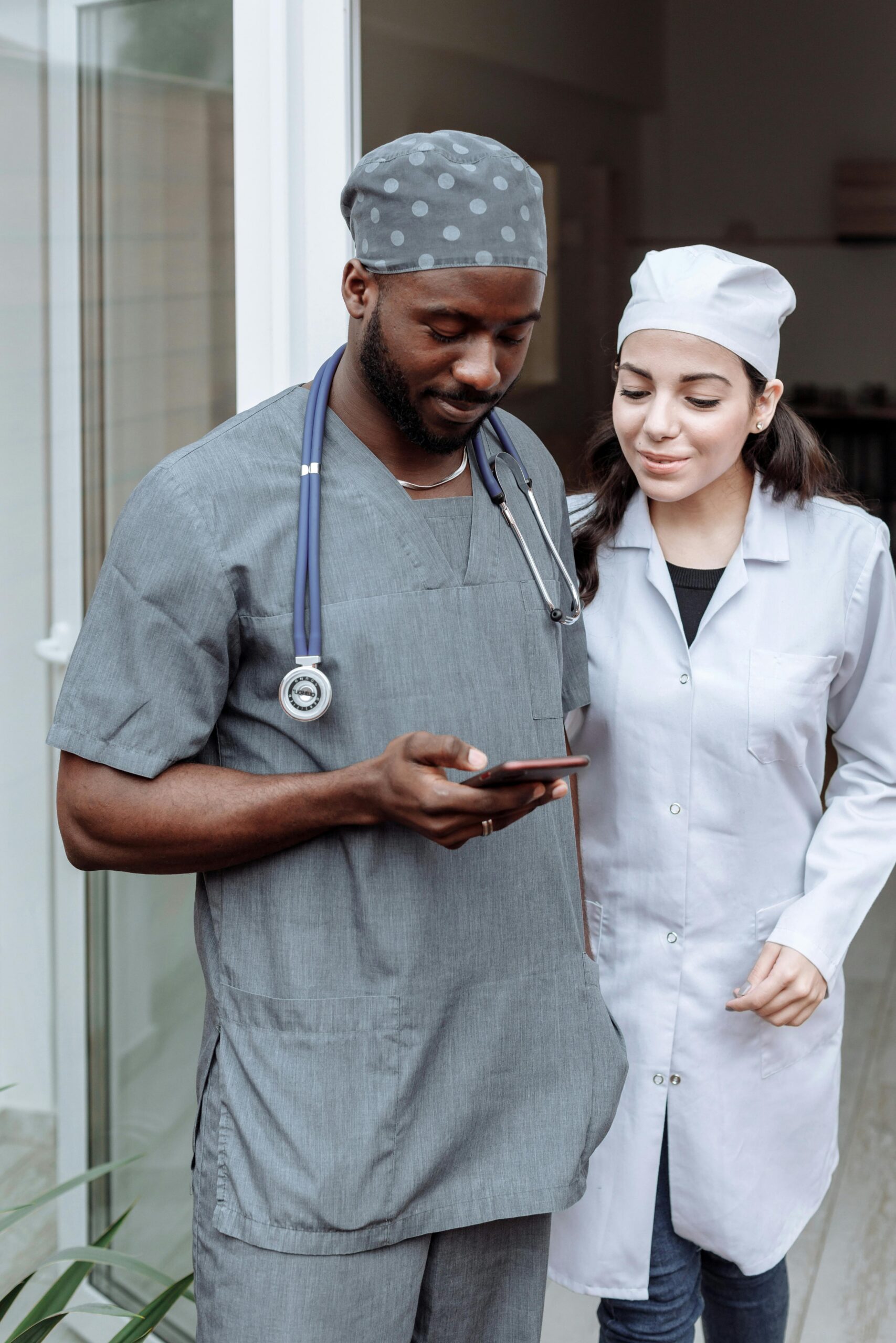 Two healthcare professionals in scrubs discussing patient care via smartphone.